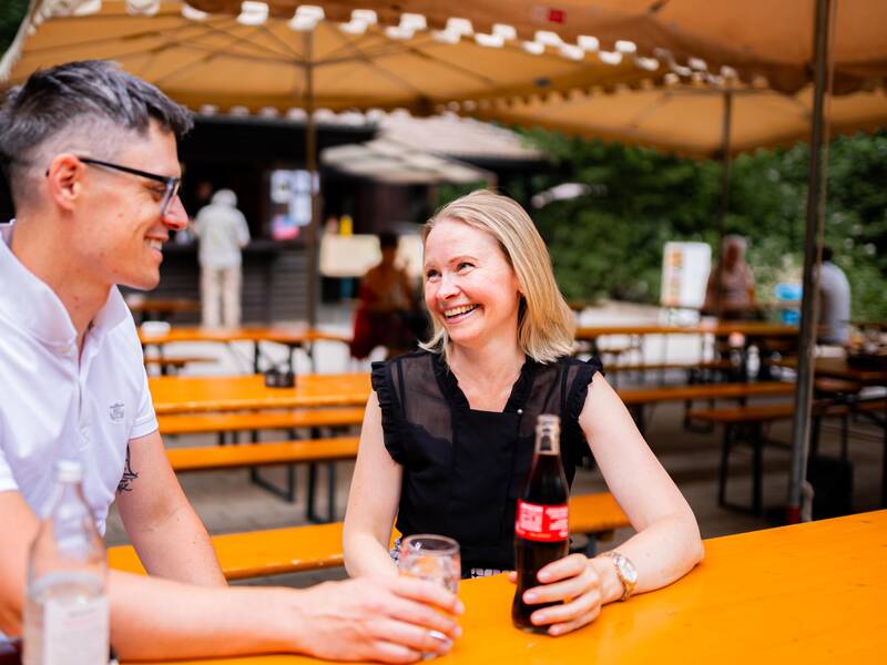 Eine Frau und ein Mann sitzen an einem Biertisch. 