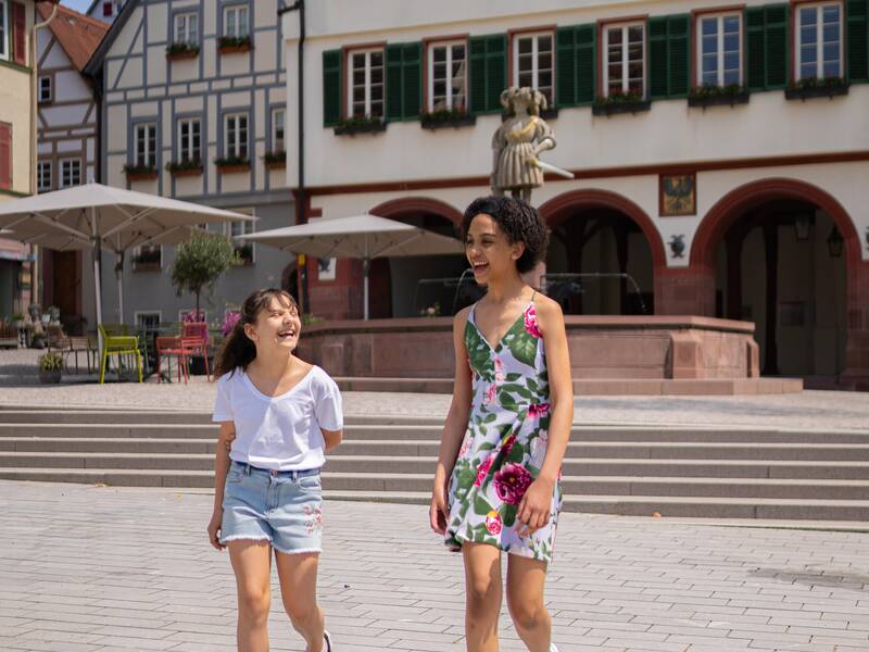 Zwei junge Leute laufen über den Marktplatz..